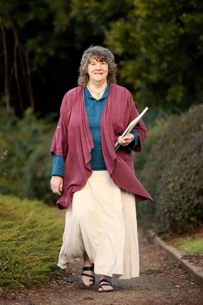 Artist, Roslyn Hartwig walking through a park.